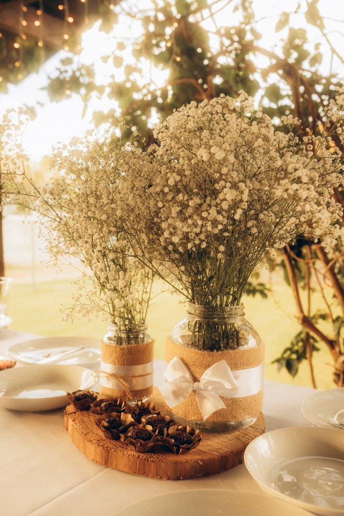 Charming rustic wedding table setting with baby's breath in vases during sunset.